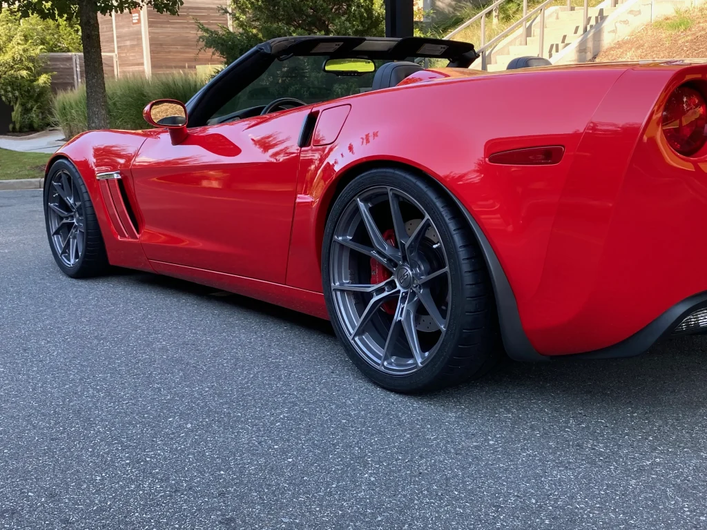 Red C6 Corvette with E5 aftermarket wheels driving on the road